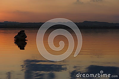 Sunset reflected in the water of the lake, the silhouette of the stone Stock Photo