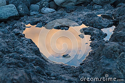 Sunset reflection in small puddle on volcanic ground Stock Photo