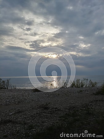 Sunset Rocks Lake trees pebbles waves water sky clouds vegetation beach evening view scenic Stock Photo
