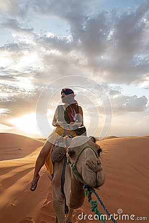 Sunset in Sahara desert with a woman in a camel Stock Photo