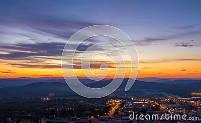 Sunset scene with mountains in background and city Matera in foreground, industrial view Stock Photo