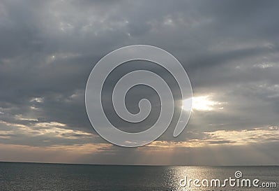 Sunset on sea with grey cloudy sky, rays of light Stock Photo