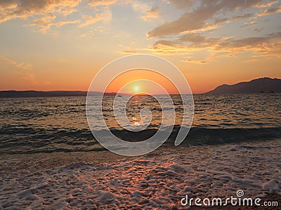 Sunset on the seashore, the setting sun is reflected on the wet sand and on the surface of the water Stock Photo