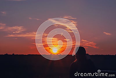 Silhouette of a girl, sky and clouds, beautiful sunset, field, pink and orange sunset Stock Photo