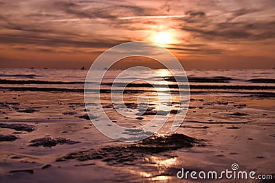 Sunset, small rock at low tide in front of the illuminated sea. Baltic Sea Stock Photo