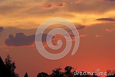 Sunset with some clouds a silhouettes of trees on the horizon Stock Photo