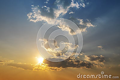 Sunset with sun and clouds on blue and orange dramatic sky with sun rays Stock Photo