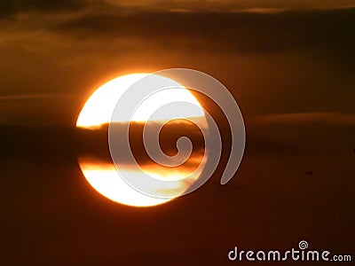 Sunset with sun and overlapping cloud. Spring scene. Sun hiding in clouds in dusk sky. Overcast floating cloudscape partially Stock Photo