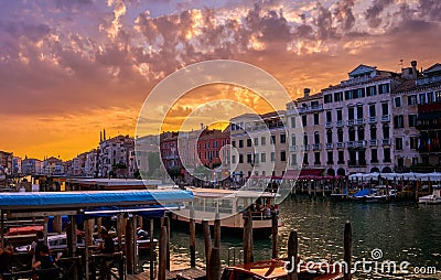 Sunset view of Grand Canal, Venice, Italy. Vaporetto or waterbus station, boats, gondolas moored by walkways, beautiful Stock Photo