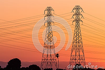 Sunset view of high voltage electricity towers on the shoreline of San Francisco bay area; California Stock Photo