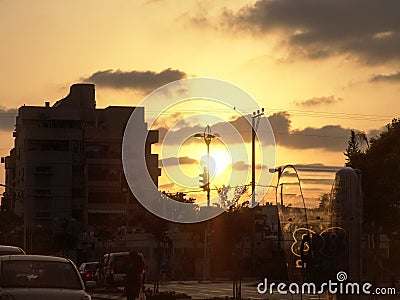 Sunset view of a town street phone booth, cars parked and real people on their way Editorial Stock Photo