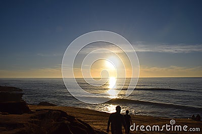 Sunset walk along beach with waves Stock Photo