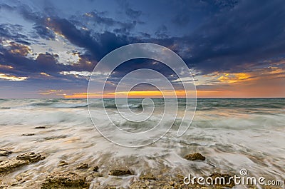 Sunset and the waves lapping on the rocky shore Stock Photo