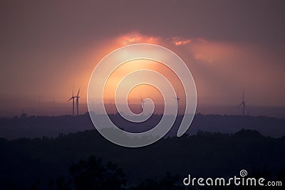 Sunset with wind turbines in a distant landscape Stock Photo