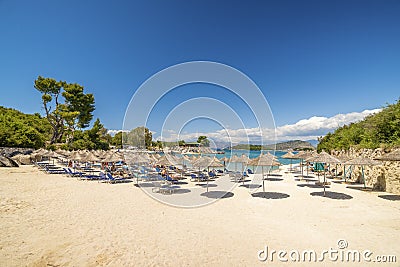 Sunshade umbrellas and deckchairs on the small beautiful Ksamil beach, Albania. Editorial Stock Photo