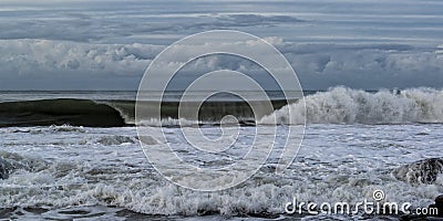 Sunshine Coast with crashing waves during a storm under a blue cloudy sky Stock Photo