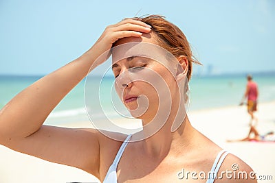 Sunstroke woman on sunny beach. Woman with headache. Hot sun danger. Health problem on holiday Stock Photo