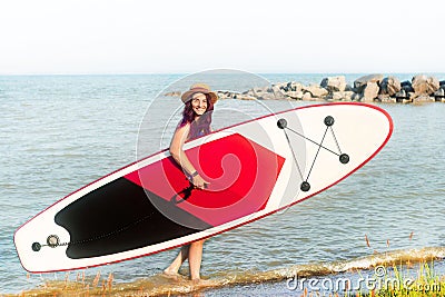 Sup boarding. A woman in a hat walks with a sup board. Stock Photo