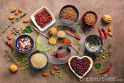 Super food background, a variety of cereals, legumes, spices, herbs, nuts. Various seasonings for cooking on brown background. Top Stock Photo