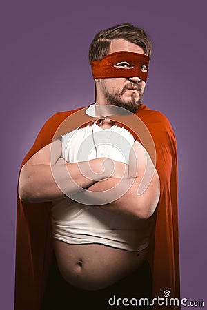 Super hero man with crossed arms and opened tummy looking at camera. Serious man in cape and superhero costume Stock Photo