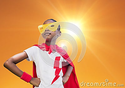 Super kid in red cape and yellow mask standing with hand on hip against bright sunlight Stock Photo