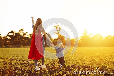 Super mom and her son walk forward holding hands. Cheerful family, a woman in a red raincoat as a superhero Stock Photo