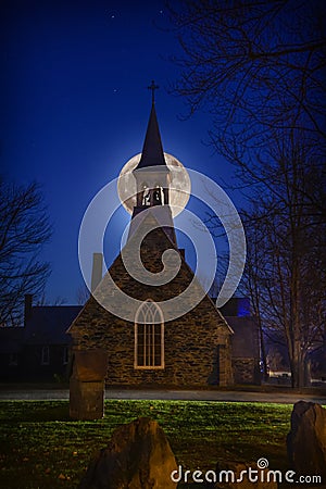 A super moon above the Anglican stone-field church, St. Peter`s of Cookshire-Eaton in Estrie, Quebec, Canada Stock Photo