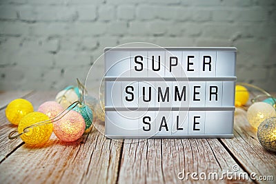 Super Summer Sale text in light box with LED cotton balls decorated on wooden background Stock Photo