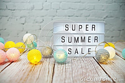 Super Summer Sale text in light box with LED cotton balls decorated on wooden background Stock Photo