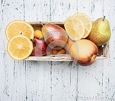 Superfoods and health or detox diet food concept variety of fruits in a wooden box kumquat, oranges, pear, lemon, top view Stock Photo
