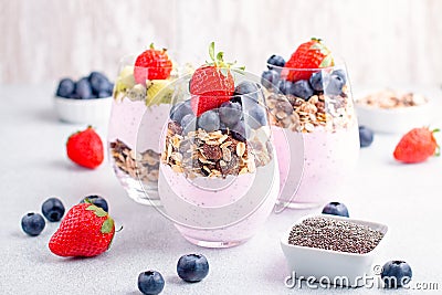 Superfoods layered pudding with granola, blueberry and strawberry in glasses. Yogurt with chia seeds, berries, kiwi and Stock Photo