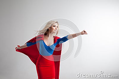 Superhero Woman. Young and beautiful blonde in image of superheroine in red Cape growing Stock Photo