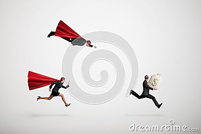 Superman and superwoman trying to catch criminals Stock Photo