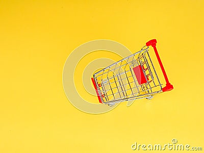 supermarket trolley on yellow background, empty, Concept of shopping. Copy space for advertisement. Stock Photo