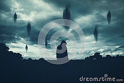 A supernatural concept. Of spirits floating above a hooded figure in the countryside at night. With a grunge, textured edit Stock Photo