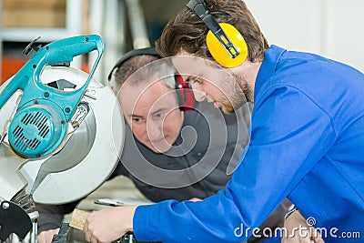 Supervisor overseeing apprentice using circular saw Stock Photo