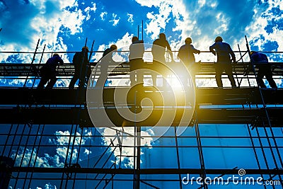 Supervisor overseeing construction crew working on tall building structure for efficient progress Stock Photo