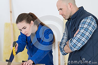 Supervisor watching apprentice use handsaw Stock Photo