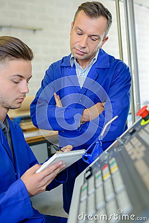 Supervisor watching younger worker writing notes Stock Photo
