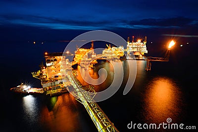 The supply boat is working at large offshore oil rig at night Stock Photo