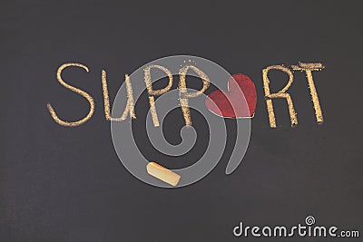 Support on chalkboard. wooden small red heart on letter O place. Stock Photo