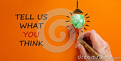 Support symbol. Businessman writing `tell us what you think`, isolated on beautiful orange background. Light bulb icon. Business Stock Photo