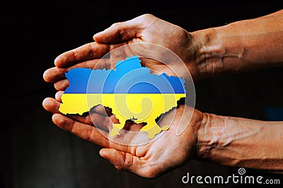 Support for Ukraine in the war with Russia. Hands holding the flag of Ukraine in the shape of the borders of Ukraine Stock Photo