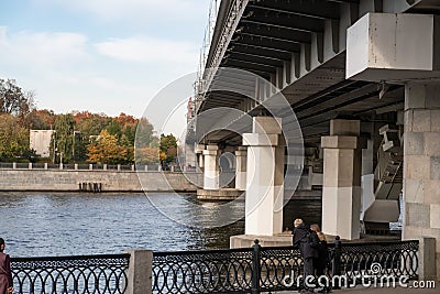 Supports of the Metro of the bridge across the Moskva river, metal fence of the embankment with granite pillars, watering, sunny Stock Photo