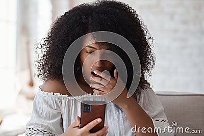 Suprized shocked woman looking at smartphone screen watching strange weird funny photo or video Stock Photo