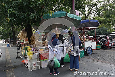 Surakarta, ID- July 16th, 2022. Several moslem woman buying Typical food from the seller on the sidewalk in front of PGS, Solo. Editorial Stock Photo
