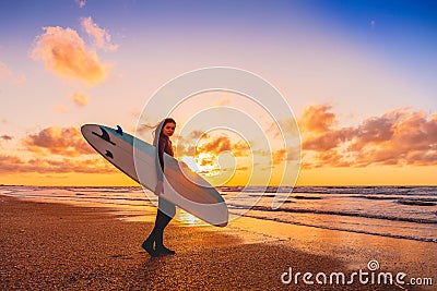Surf girl with longboard go to surfing. Woman with surfboard on a beach at sunset. Stock Photo