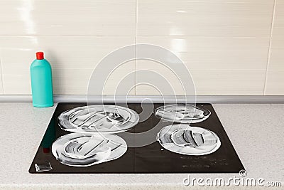 The surface of the induction stove is covered with a detergent. House cleaning - plastic bottles with detergents on kitchen tablet Stock Photo