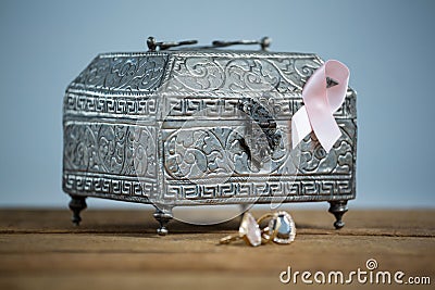 Surface level view of pink Breast Cancer Awareness ribbon with chest and rings on wooden table Stock Photo