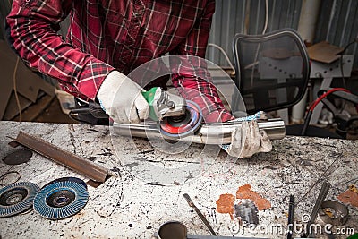 Surface preparation of stainless steel pipes using an angle grinder for further welding in an iron workshop. Industry and Stock Photo